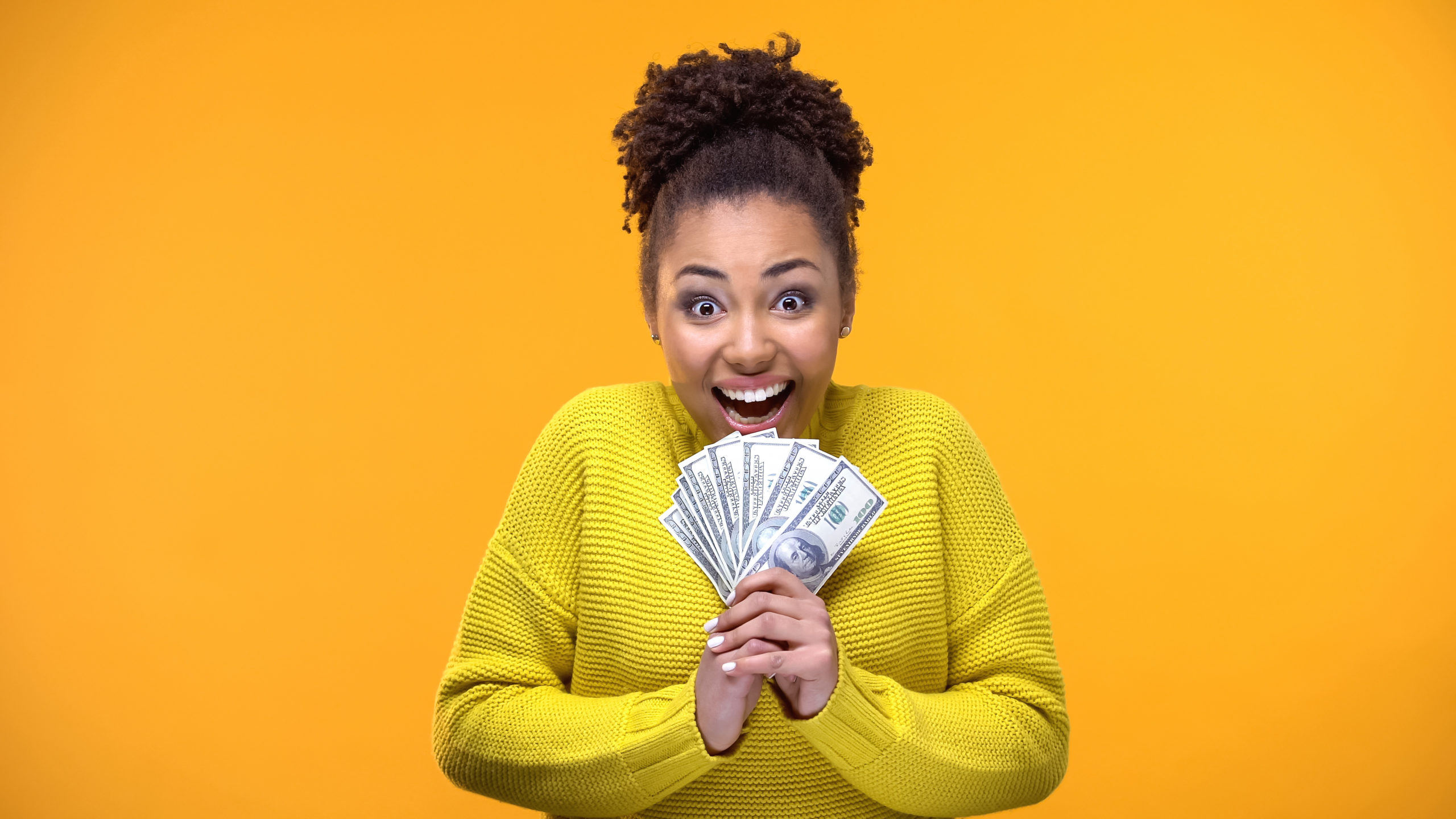 Excited woman holding a bunch of dollars